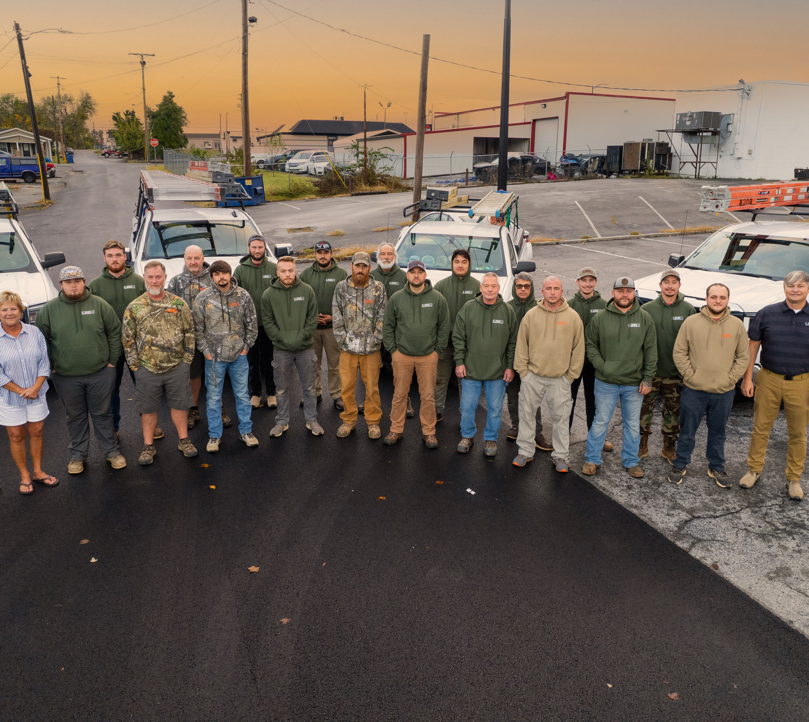 The Buck Electric crew of seventeen in front of a fleet of branded white work trucks, October 2024
